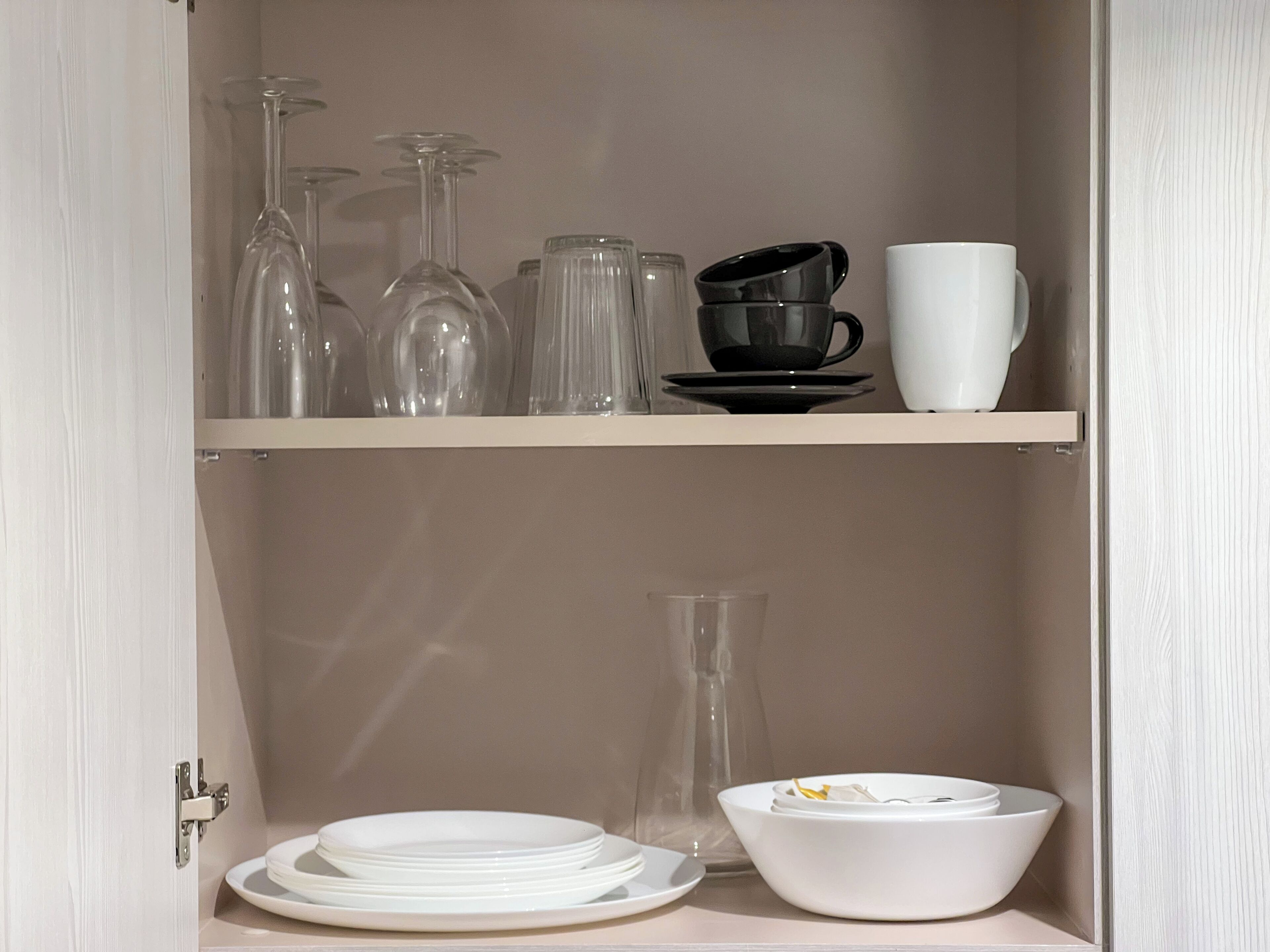 A cabinet with two shelves containing various glassware and dishes.