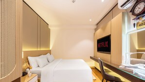 A modern hotel room with a neatly made bed, a desk with a chair, a wall-mounted TV, and a clock. - A25 Premium Hotel - 277 Le Thanh Ton (Ho Chi Minh City)