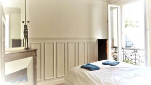 Un dormitorio con una cama, un aparador, un espejo y una ventana con vistas al exterior.
