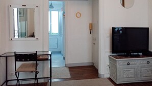 Una habitación con televisión, una mesa de comedor con una silla, un armario y dos espejos adosados a la pared.