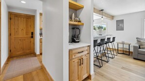 A modern kitchen with wooden cabinets, a built-in coffee machine, and a bar area with stools. - Downtown Loft 205 - Downtown McCall condo next to Payette Lake (McCall)
