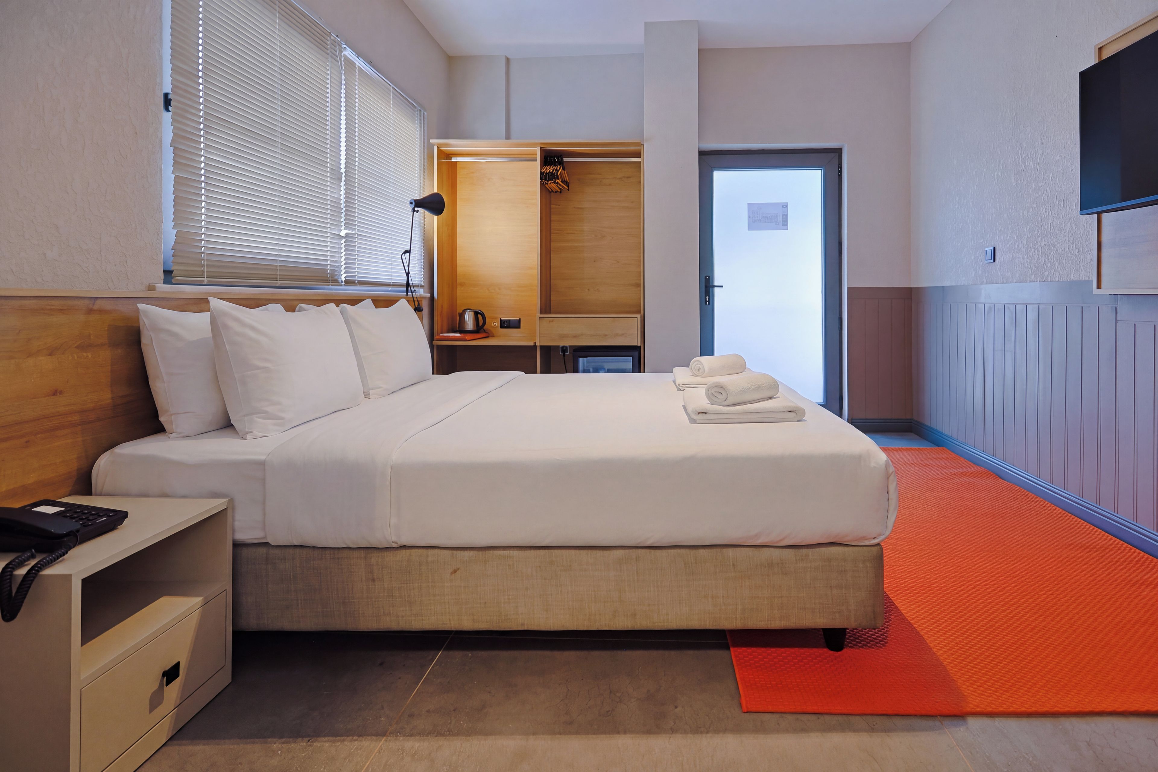 Ein Hotelzimmer mit einem Einzelbett, einem Nachttisch und einem an der Wand befestigten Fernseher.