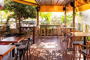 An outdoor patio area with wooden tables and chairs, surrounded by potted plants and trees. - 7 inn  (Konyaalti)