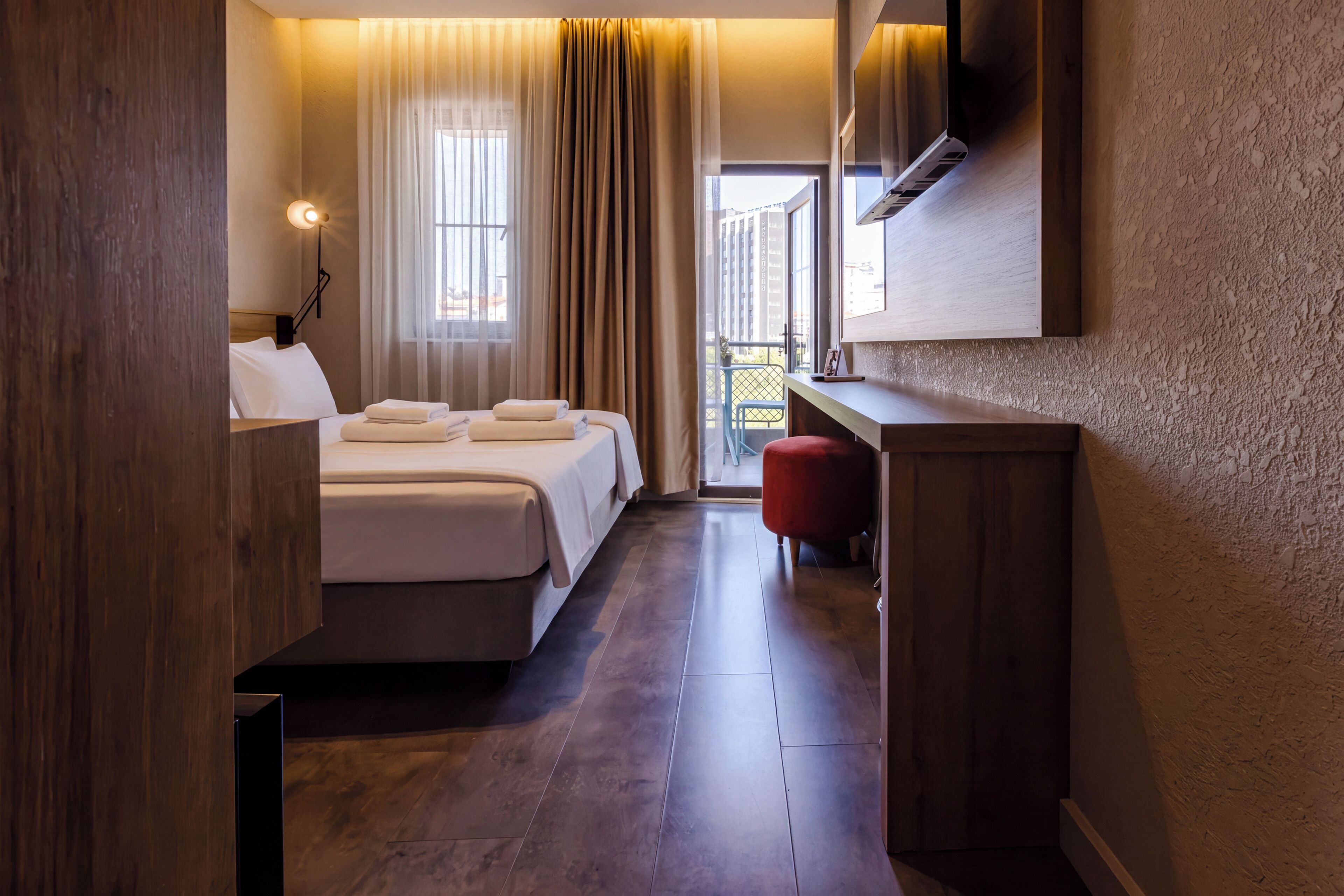 Una camera d'albergo con un letto, una scrivania, una sedia e vista sull'esterno.