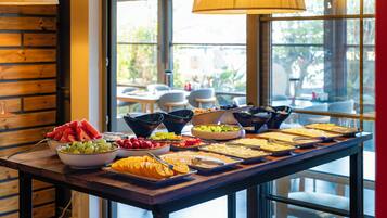 A buffet table with various food items and a window view.