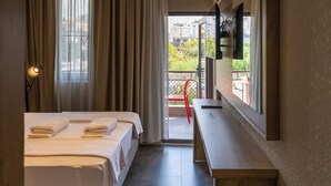 A hotel room with two beds, a desk, a TV, and a balcony with a red chair. - 7 inn  (Konyaalti)
