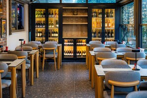 A restaurant interior with multiple tables and chairs, a wine display case, and a view through the windows. - 7 inn  (Konyaalti)
