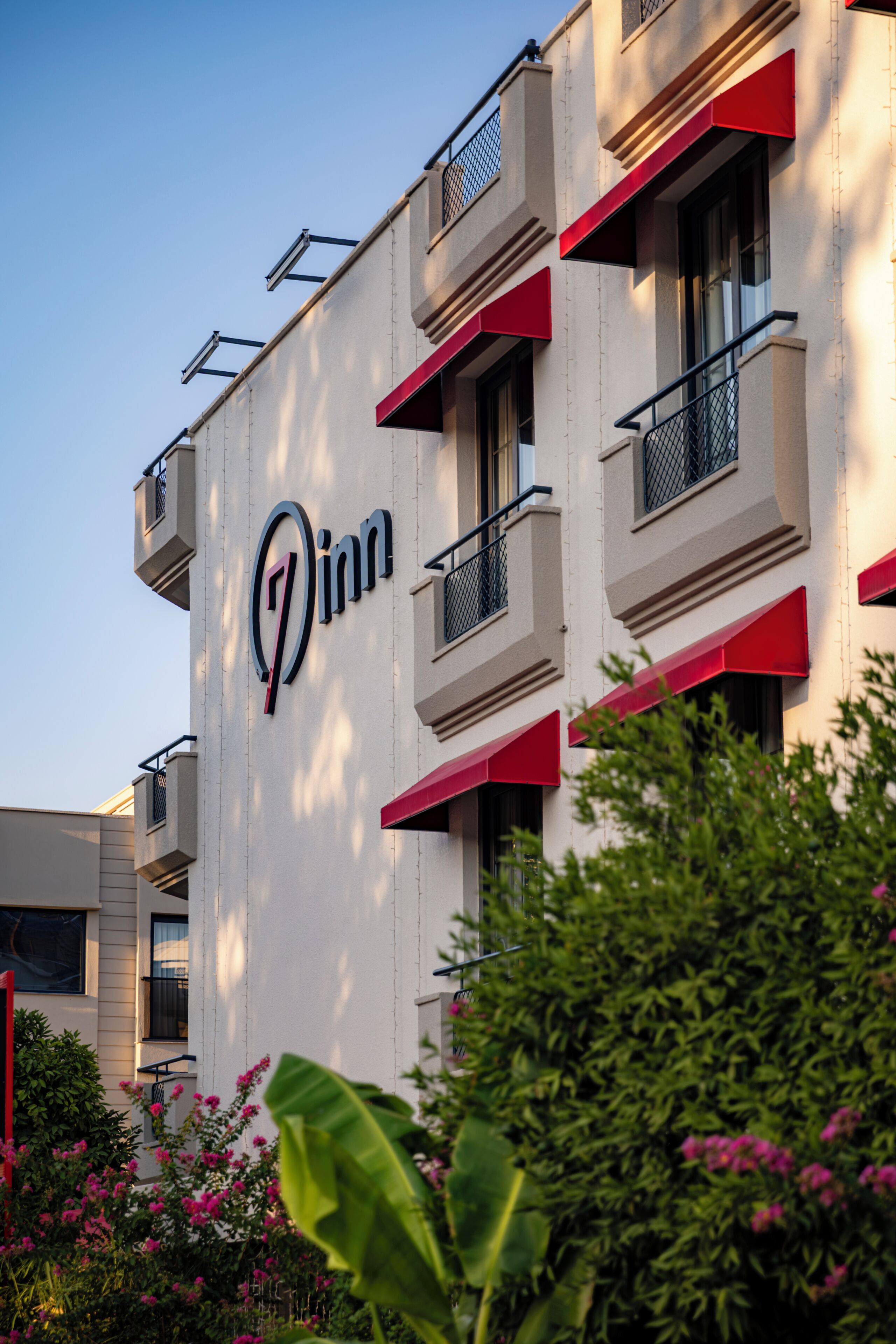 A building with a prominent '7 Inn' sign, multiple balconies, and a clear sky.