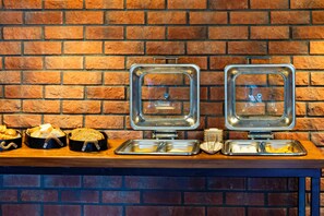 A buffet setup with bread, eggs, and other breakfast items on a wooden table against a brick wall. - 7 inn  (Konyaalti)