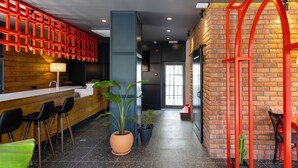 A modern interior with a reception desk, black chairs, potted plants, and a red decorative structure. - 7 inn  (Konyaalti)