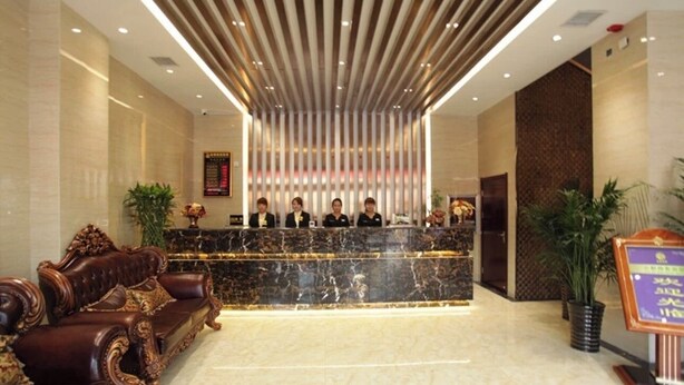 A reception area with a marble counter, a leather sofa, and a vertical light fixture. - Yundu Business Hotel (Xianyang)