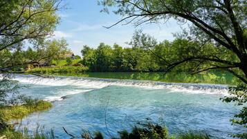 A river with a waterfall, surrounded by lush greenery and trees.
