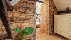Un interior de madera con una cama, un aparador y una planta grande.