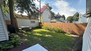A backyard with a wooden deck, a picnic table, and a small garden area. - Strikeout - All Star Baseball Rentals (Oneonta)