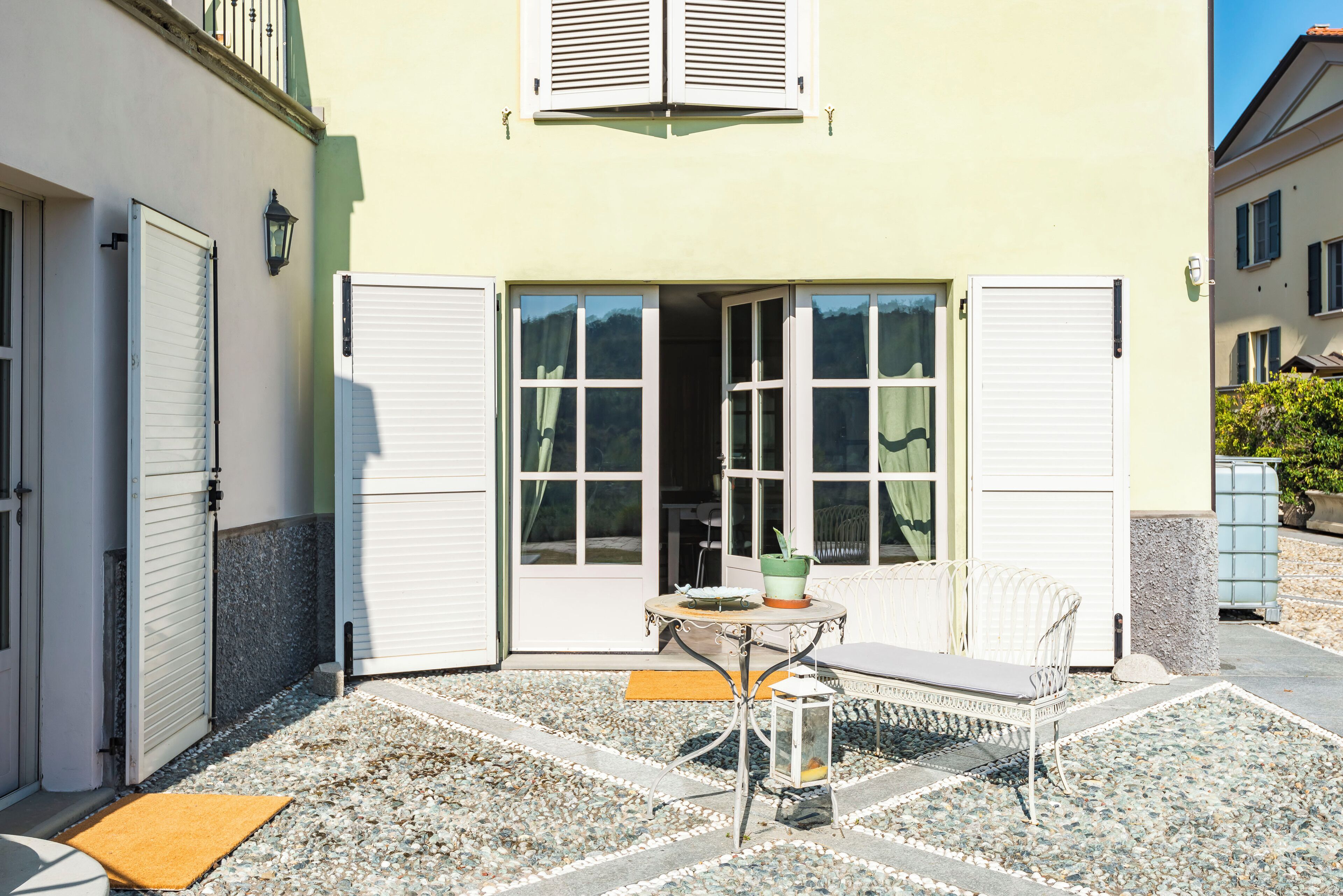 Una casa con patio amoblado, que incluye una mesa, una silla y un farol.