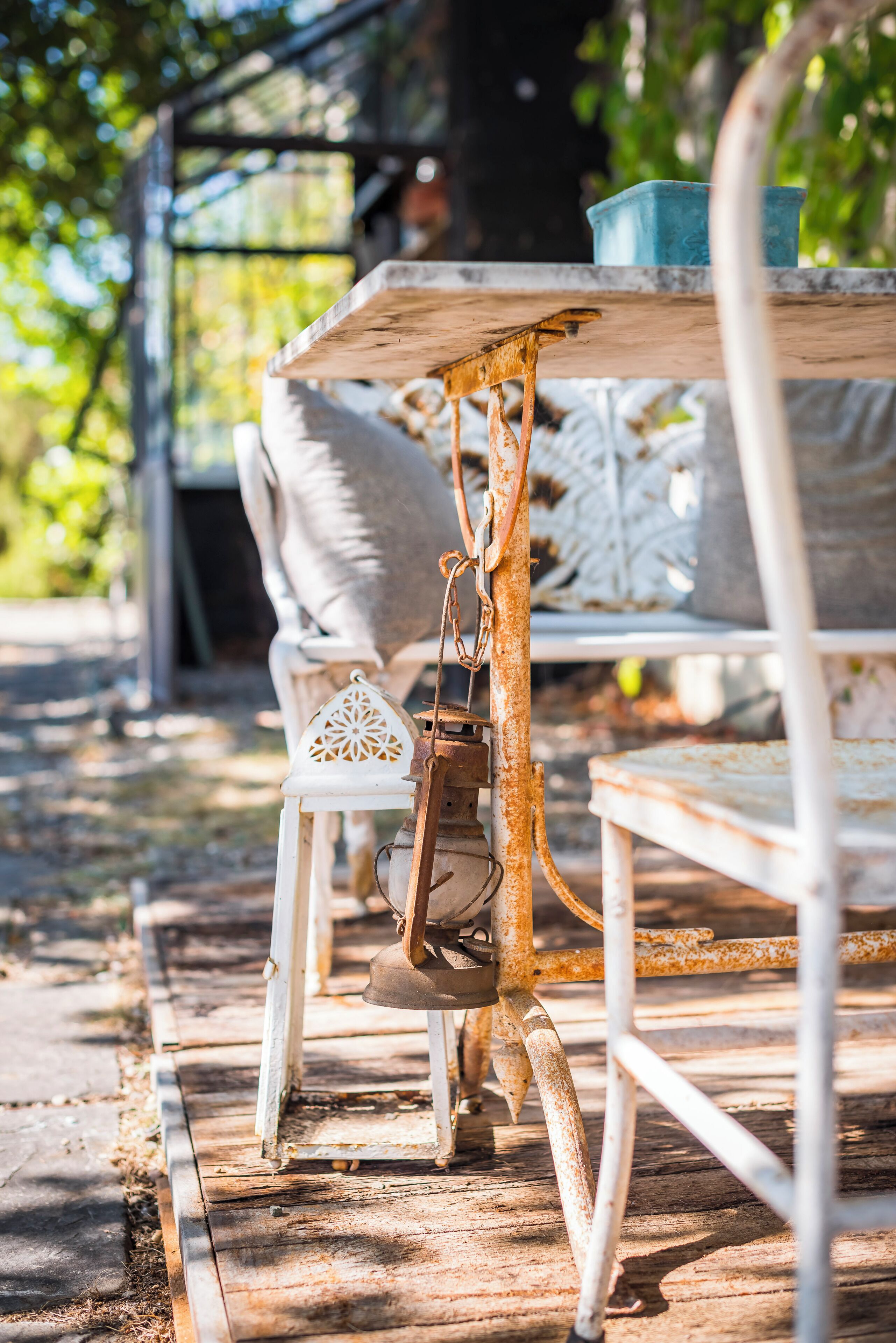 A rustic outdoor seating area with metal chairs and a table, surrounded by greenery.