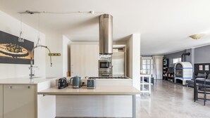 Una cuina moderna amb una illa central, forn encastrat i campana extractora d'acer inoxidable.