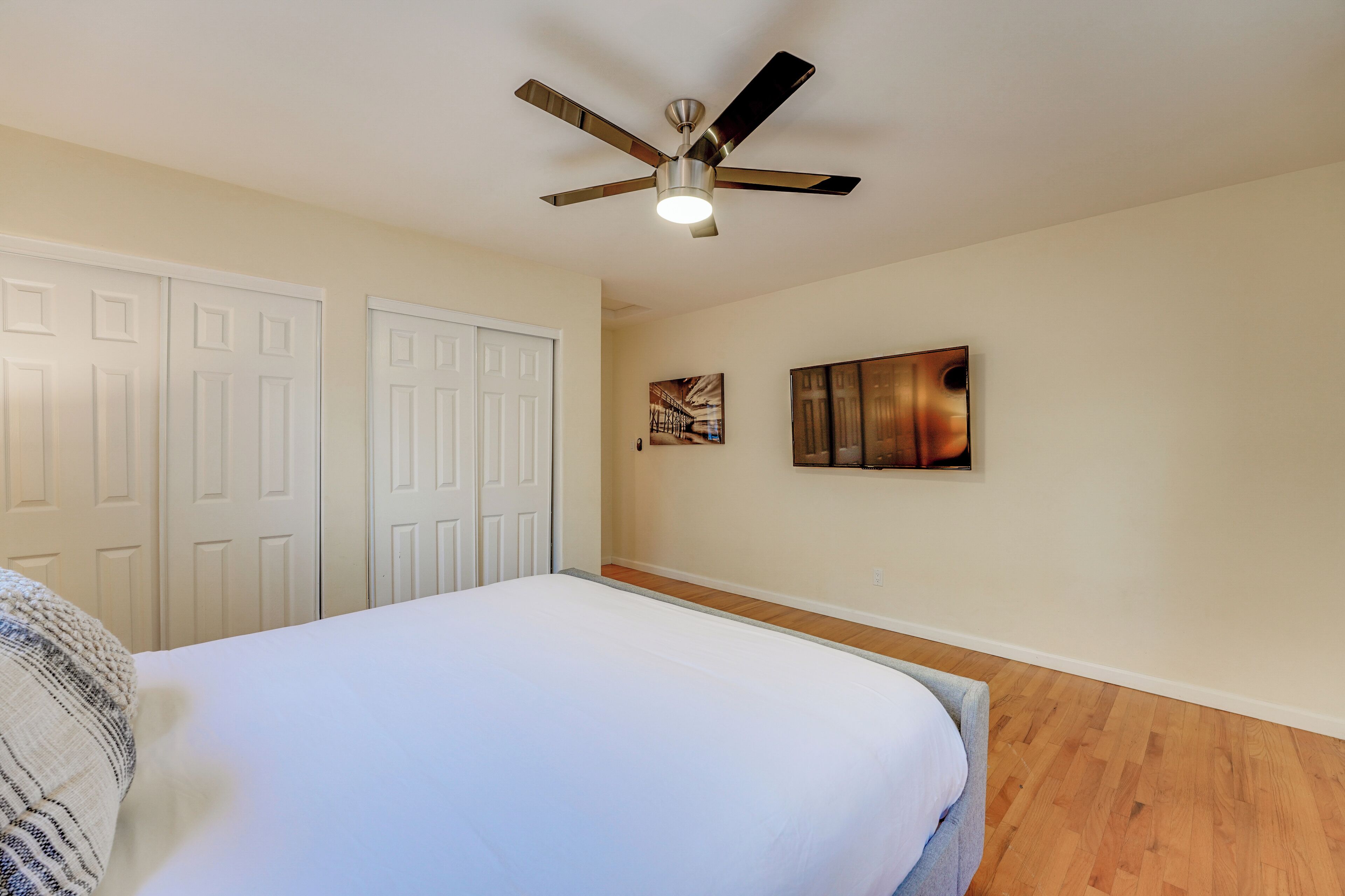Un dormitorio con cama, ventilador de techo y piso de madera.