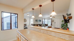 A kitchen with a large island, pendant lights, and a view of the outdoors.
