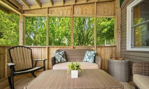 A wooden deck with a table, chairs, and a sofa with cushions.