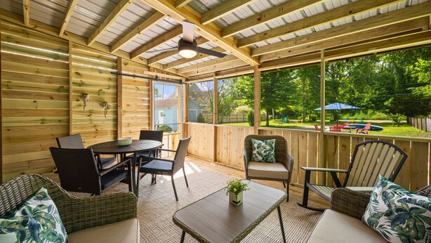 A covered patio with wooden beams, a ceiling fan, and outdoor furniture. - Short Description: Lakewood Bungalow | Screened Porch • 2 Baths • Basement Hangout • Walk to Lake• Onsite Laundry (Coloma charter Township)