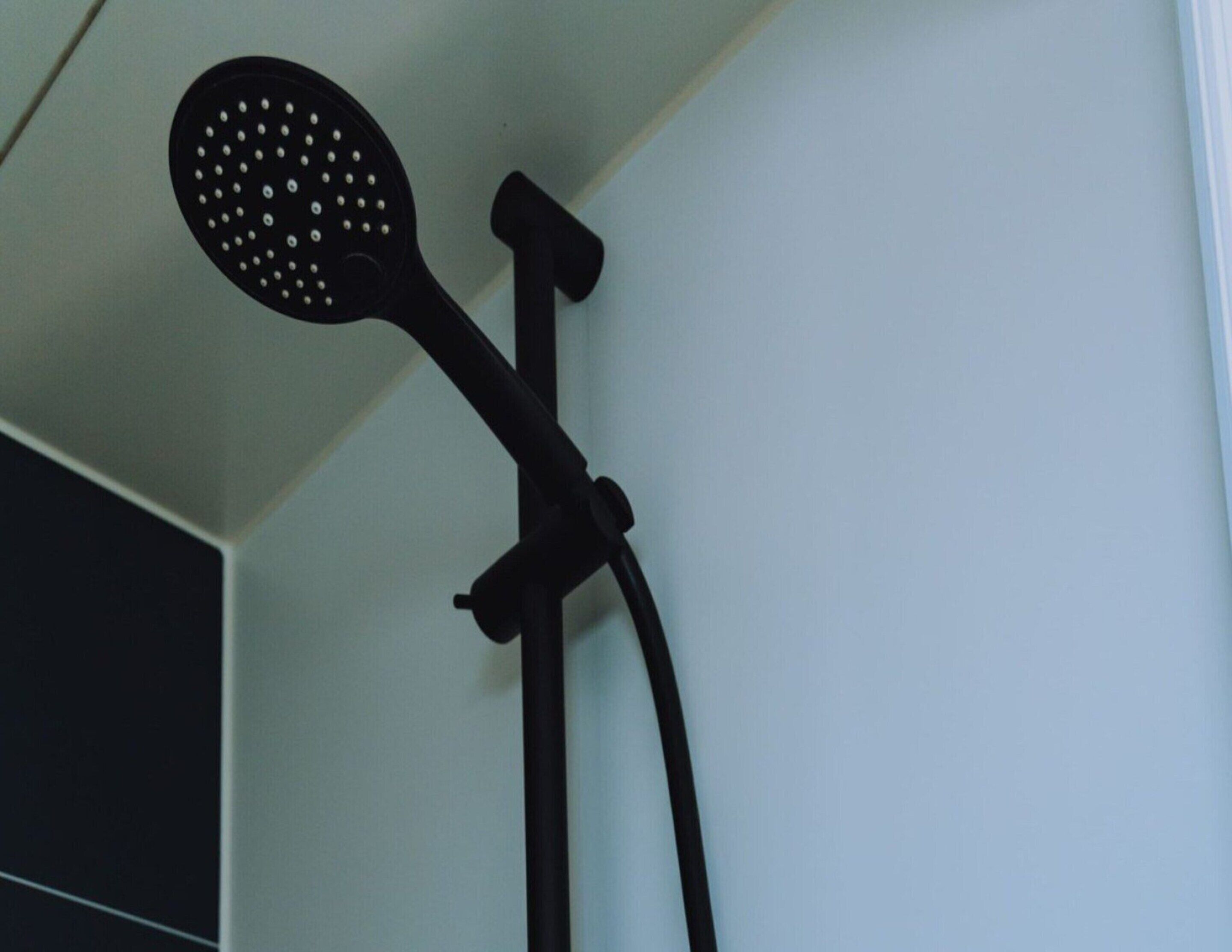 Un pommeau de douche de forme circulaire, doté de plusieurs jets, fixé au mur d’une salle de bain.