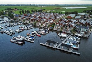 A marina with boats docked, surrounded by residential houses with red brick facades and pitched roofs.