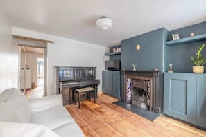 Un salon avec un piano, une cheminée et un canapé.