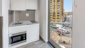 Una cocina moderna con horno empotrado, pileta de acero inoxidable y ventana con vista a una calle de la ciudad.