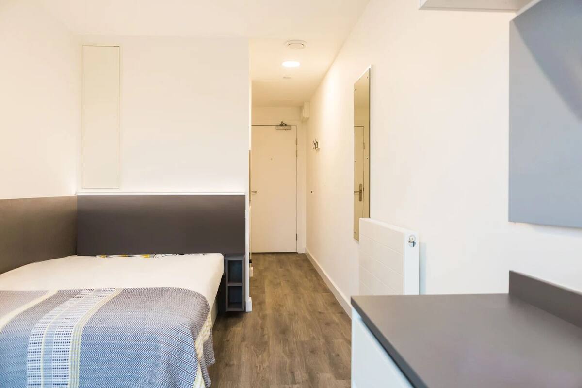 Ein modernes Hotelzimmer mit Bett, kleinem Schreibtisch und begehbarem Kleiderschrank.