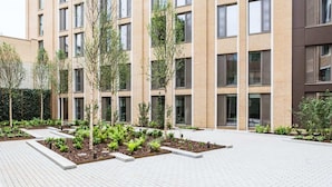 Un edificio moderno con múltiples ventanales y un patio ajardinado con árboles y plantas.