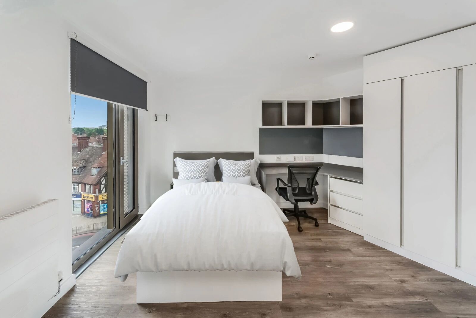 Un dormitorio moderno con una cama grande, un escritorio y estanterías empotradas.