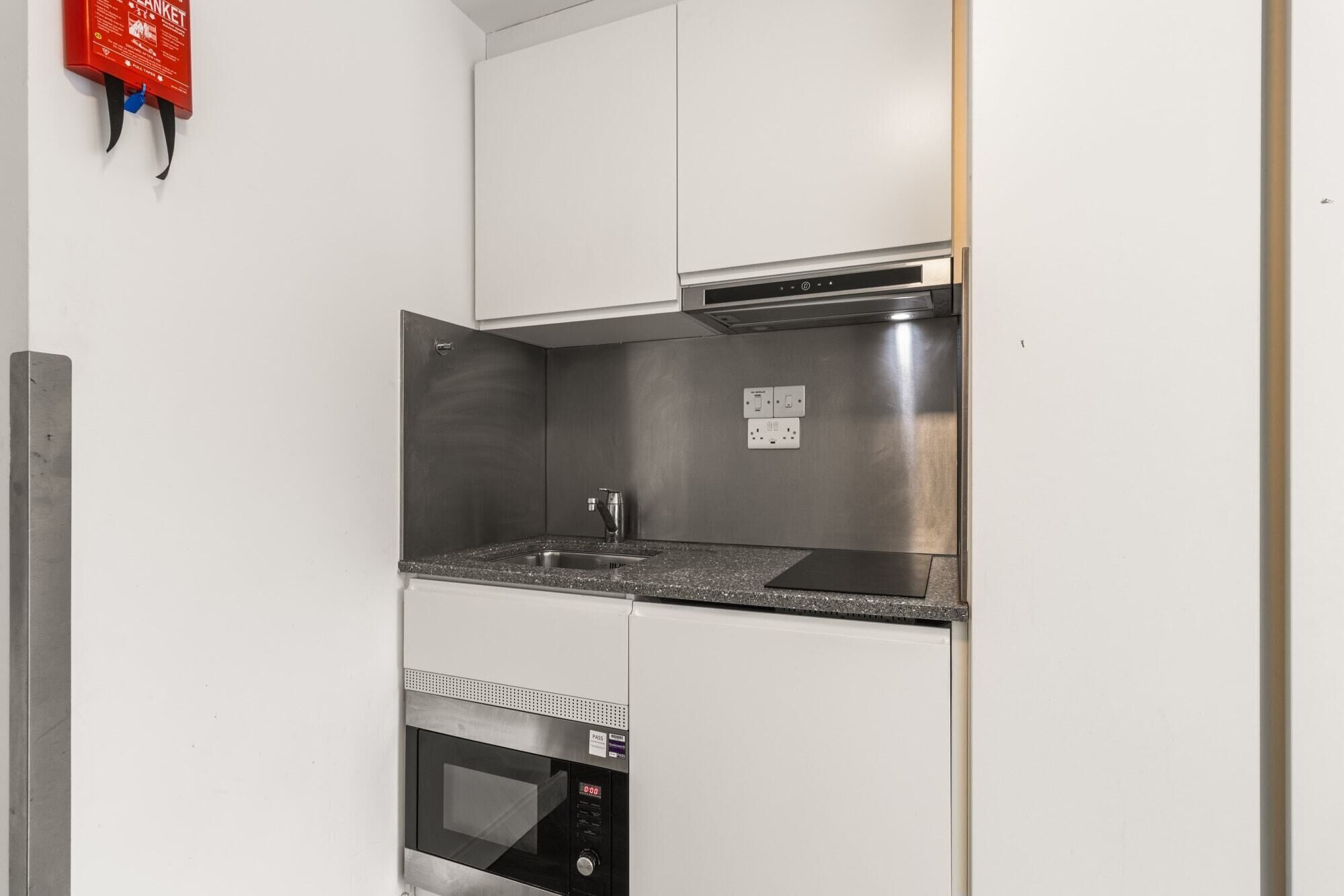 A compact kitchen with a built-in microwave, oven, and a small sink.