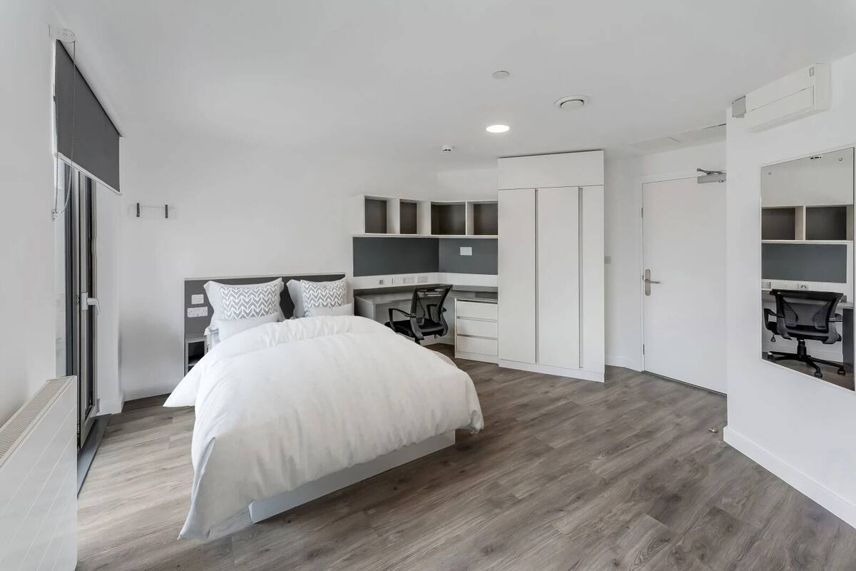 Ein modernes Schlafzimmer mit Bett, Schreibtisch und Kleiderschrank.