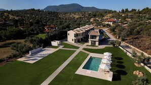 A modern villa with a swimming pool, surrounded by well-maintained lawns and olive trees. - SeaSide Village (Dirfys-Messapia)