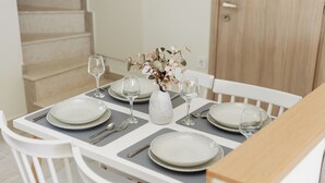 A dining table set with plates, glasses, and a vase with flowers. - SeaSide Village (Dirfys-Messapia)
