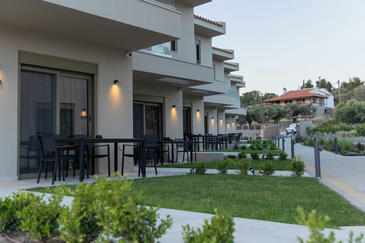 Een modern hotel met terras, een verzorgde tuin en uitzicht op het omliggende landschap.