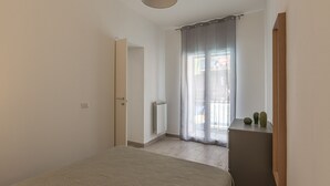 A bedroom with a bed, a radiator, a window with curtains, and a small cabinet with decorative items. - La Casa sul Mercato by Wonderful Italy (Palermo)