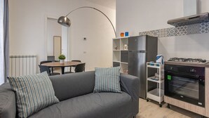 A modern kitchen with a built-in oven, a gas stove, and a refrigerator. There is a dining area with a table and chairs, and a sofa with striped cushions. - La Casa sul Mercato by Wonderful Italy (Palermo)