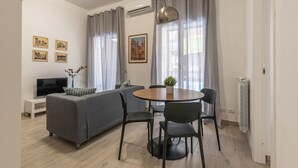 A modern living room with a grey sofa, a TV, a dining table with chairs, and a pendant light. - La Casa sul Mercato by Wonderful Italy (Palermo)