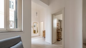 Une chambre d’hôtel moderne avec un canapé gris, une armoire en bois et un miroir au mur.