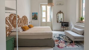 Une chambre à coucher avec un lit, un canapé, une télévision et une fenêtre.