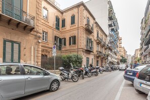 Een rij geparkeerde auto's en motorfietsen op een stadsstraat met meerlaagsgebouwen.
