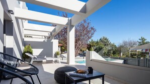 A modern outdoor patio with a pool, lounge chairs, and a table with a croissant and coffee cup. - Akonizia Luxury House - With Private Swimming Pool (Apokoronas)
