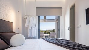 A modern hotel room with a large bed, a view of the outdoors, and a balcony with seating. - Akonizia Luxury House - With Private Swimming Pool (Apokoronas)