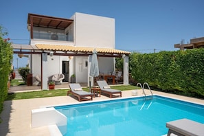 A modern house with a swimming pool, outdoor furniture, and a covered patio area.