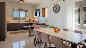 A modern kitchen with dark cabinets, a central island, and a dining area with a wooden table and chairs.
