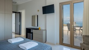 A modern bedroom with a bed, a desk, a TV, and a balcony with a table and chairs.