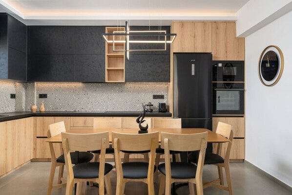 Une cuisine moderne avec une table et des chaises de salle à manger en bois, un réfrigérateur noir et un four à micro-ondes.