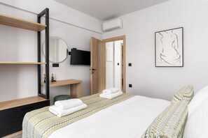 Une chambre d’hôtel comprenant un lit, un bureau avec une chaise, une télévision, une armoire et un tableau au mur.